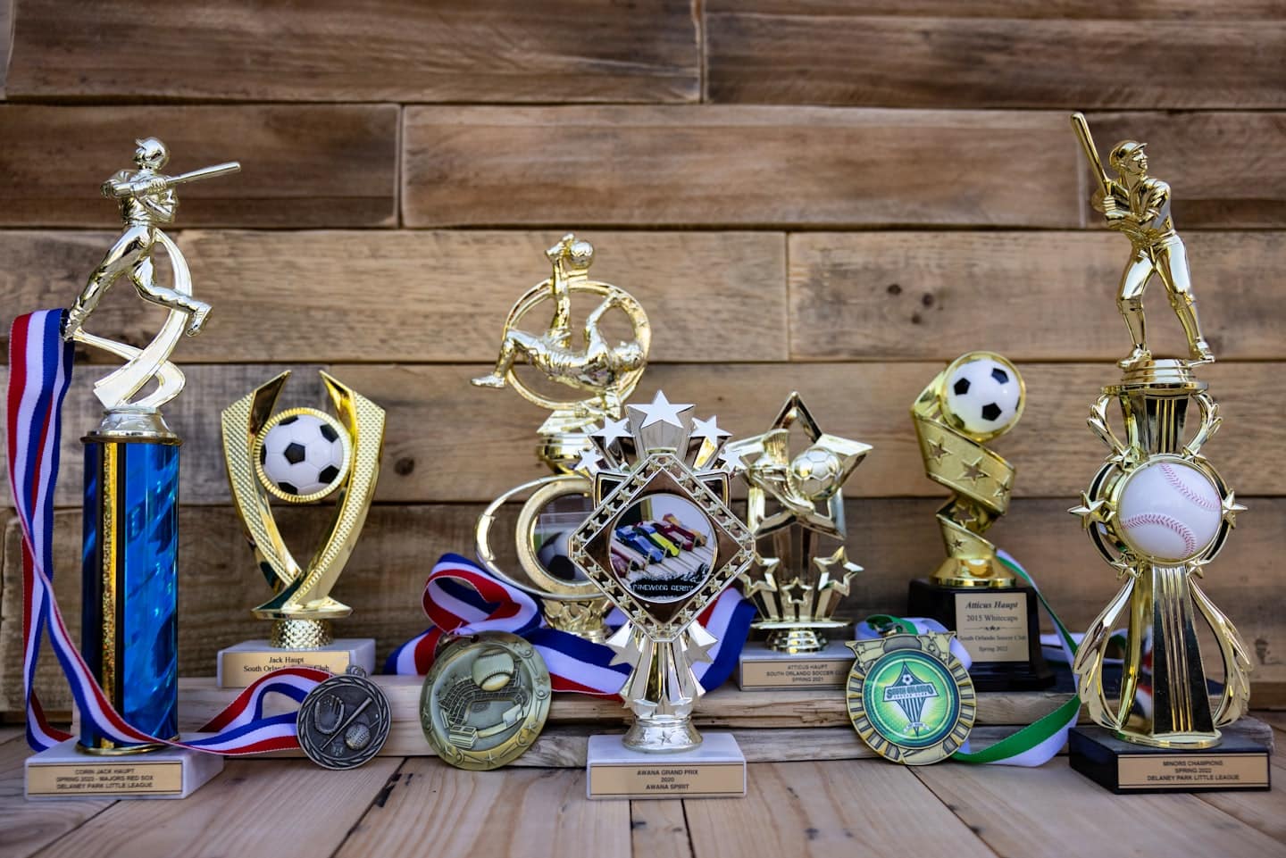 Športové trofeje a medaily na rustikálnom drevenom stole.